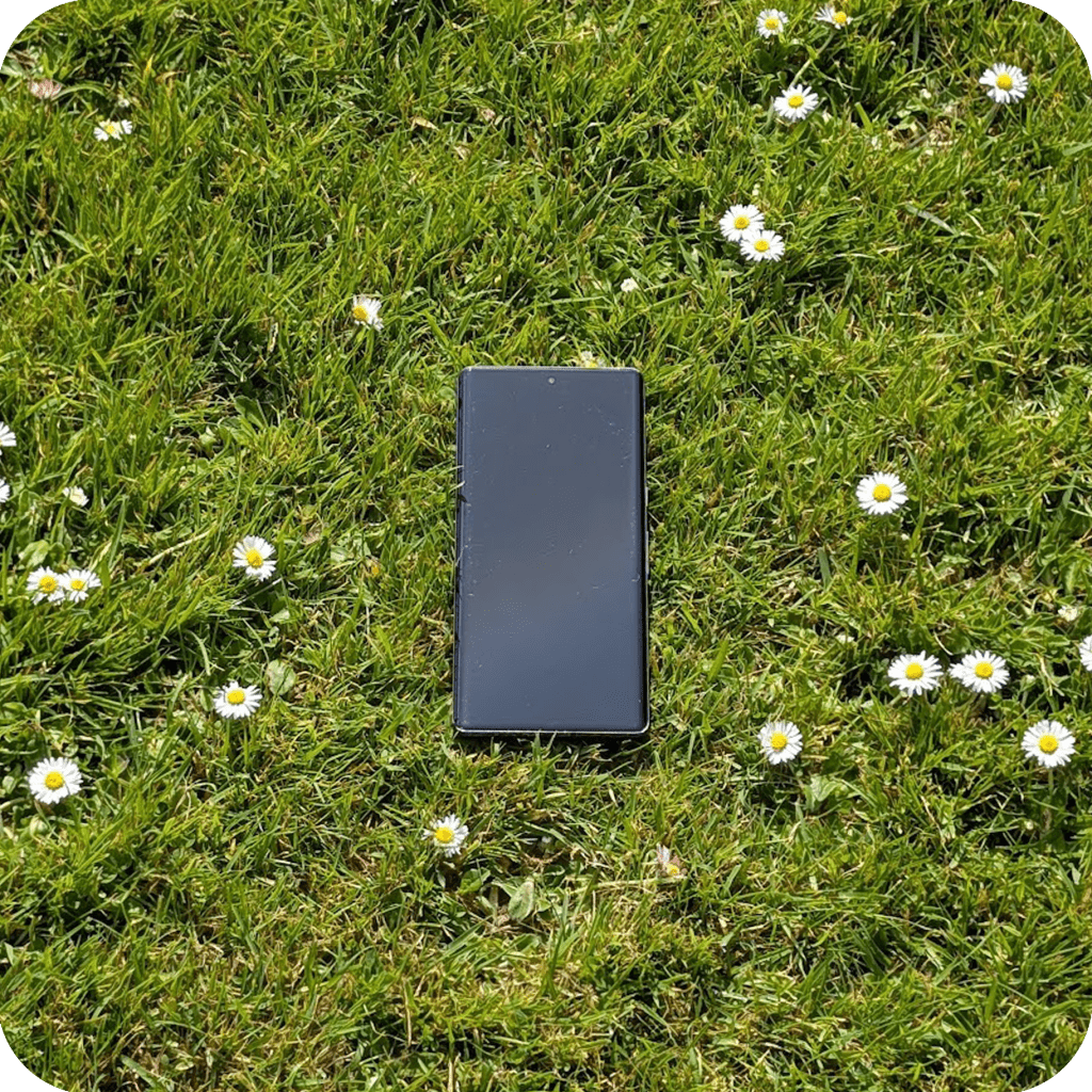 a phone in grass with daisies around it